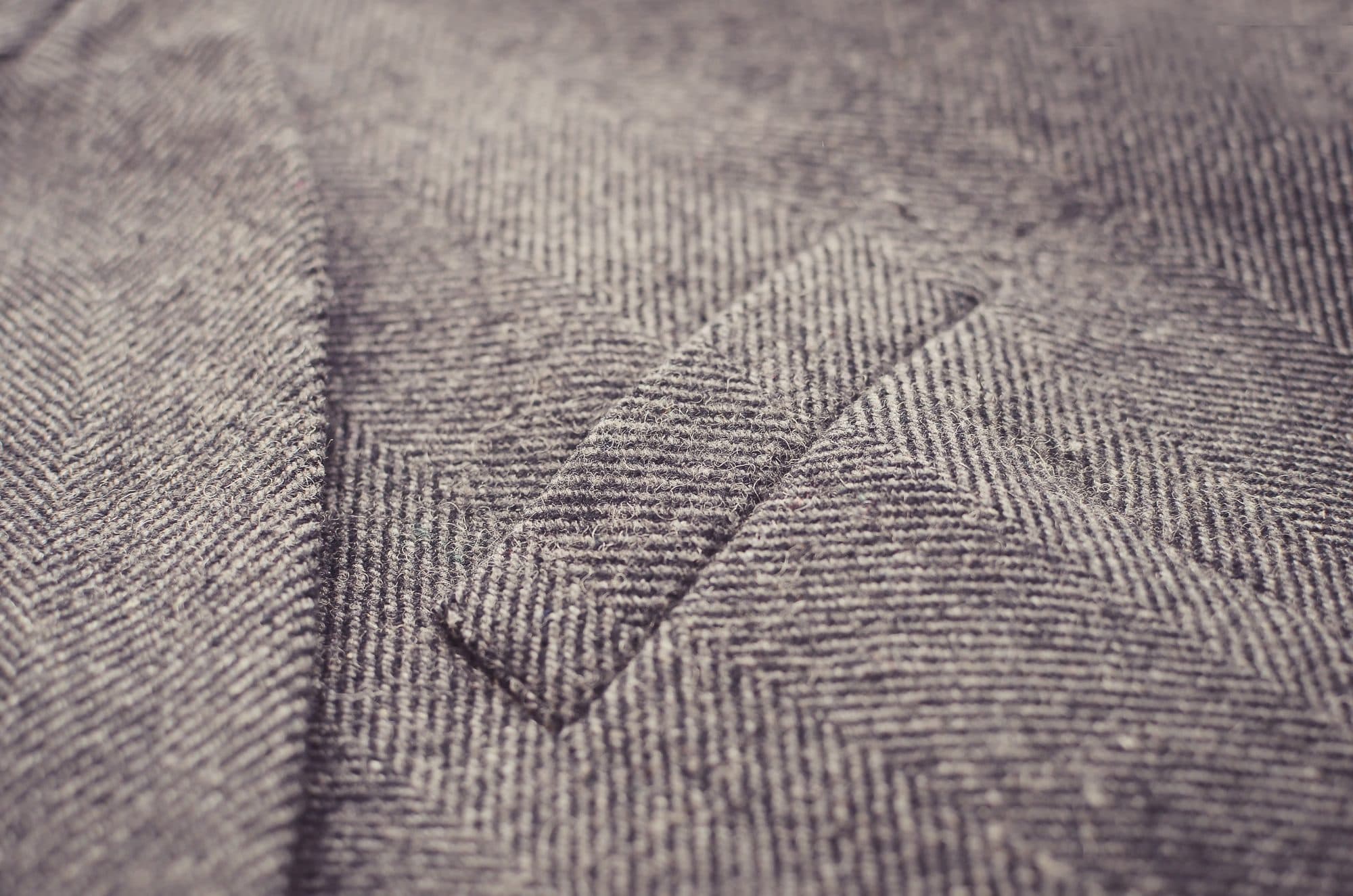 Detalle macro de una chaqueta de espiga gris con bolsillo de vivo